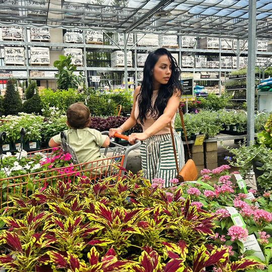Woman and child shopping in a greenhouse wearing a Metro Crossbody.