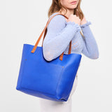 Astro Blue Classic | Model holding large leather tote bag with sturdy bridle handles and front pocket