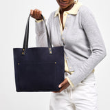 Velvet Blue Classic | Model holding large leather tote bag with sturdy bridle handles and front pocket