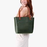 Evergreen Classic | Model holding large leather tote bag with sturdy bridle handles and front pocket
