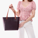 Larkspur Classic | Model holding large leather tote bag with sturdy bridle handles and front pocket