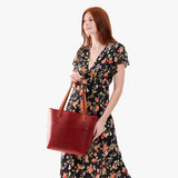 Phoenix Classic | Model holding large leather tote bag with sturdy bridle handles and front pocket