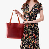 Phoenix Classic | Model holding large leather tote bag with sturdy bridle handles and front pocket