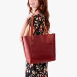 Phoenix Classic | Model holding large leather tote bag with sturdy bridle handles and front pocket