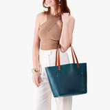 Westward Blue Classic | Model holding large leather tote bag with sturdy bridle handles and front pocket