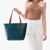 Westward Blue Classic | Model holding large leather tote bag with sturdy bridle handles and front pocket