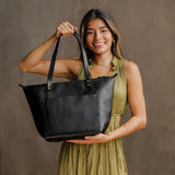 Pebbled--black Zipper | Model holding large zipper leather tote bag with sturdy bridle handles and front pocket