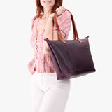 Larkspur Zipper | Model holding large leather tote bag with sturdy bridle handles and front pocket