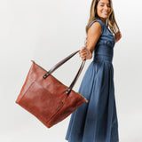 Nutmeg Zipper | Model holding large zipper leather tote bag with sturdy bridle handles and front pocket
