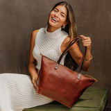 Nutmeg Zipper | Model holding large zipper leather tote bag with sturdy bridle handles and front pocket