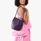 Empire Classic | Model wearing sleeveless pink dress carrying petite bucket shaped tote bag with matching leather handles