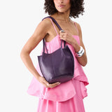 Empire Classic | Model wearing sleeveless pink dress holding petite bucket shaped tote bag with matching leather handles