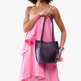 Empire Classic | Model wearing sleeveless pink dress holding petite bucket shaped tote bag with matching leather handles
