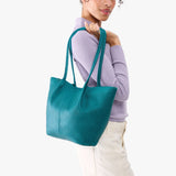 Aquarius Large | Model wearing lavender sweater and white pants carrying wide bucket shaped tote bag with matching leather handles