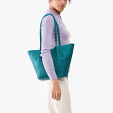 Aquarius Large | Model wearing lavender sweater and white pants carrying wide bucket shaped tote bag with matching leather handles