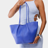 Astro Blue Large | Model holding wide bucket shaped tote bag with matching leather handles