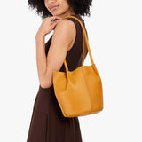 Sunshine Classic | Model wearing dark brown dress carrying petite bucket shaped tote bag with matching leather handles