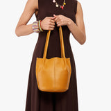 Sunshine Classic | Model wearing dark brown dress holding petite bucket shaped tote bag with matching leather handles