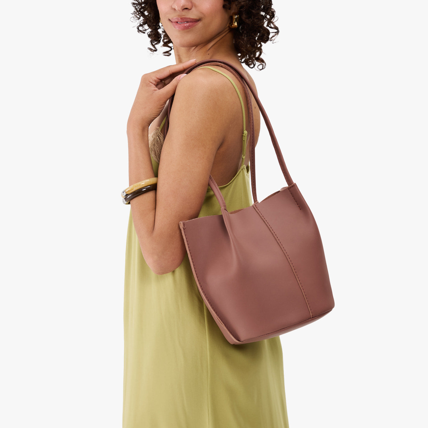 Sunkissed*Classic | Model wearing sleeveless light green dress carrying petite bucket shaped tote bag with matching leather handles