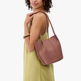 Sunkissed Classic | Model wearing sleeveless light green dress carrying petite bucket shaped tote bag with matching leather handles