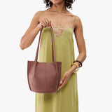 Sunkissed Classic | Model wearing sleeveless light green dress holding petite bucket shaped tote bag with matching leather handles
