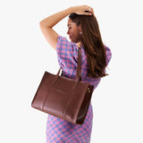 Cognac East/West | Model holding structured wide tote bag with overlapping panels and crossbody strap