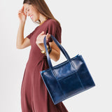 Cowboy Blue East/West | Model holding structured wide tote bag with overlapping panels and crossbody strap