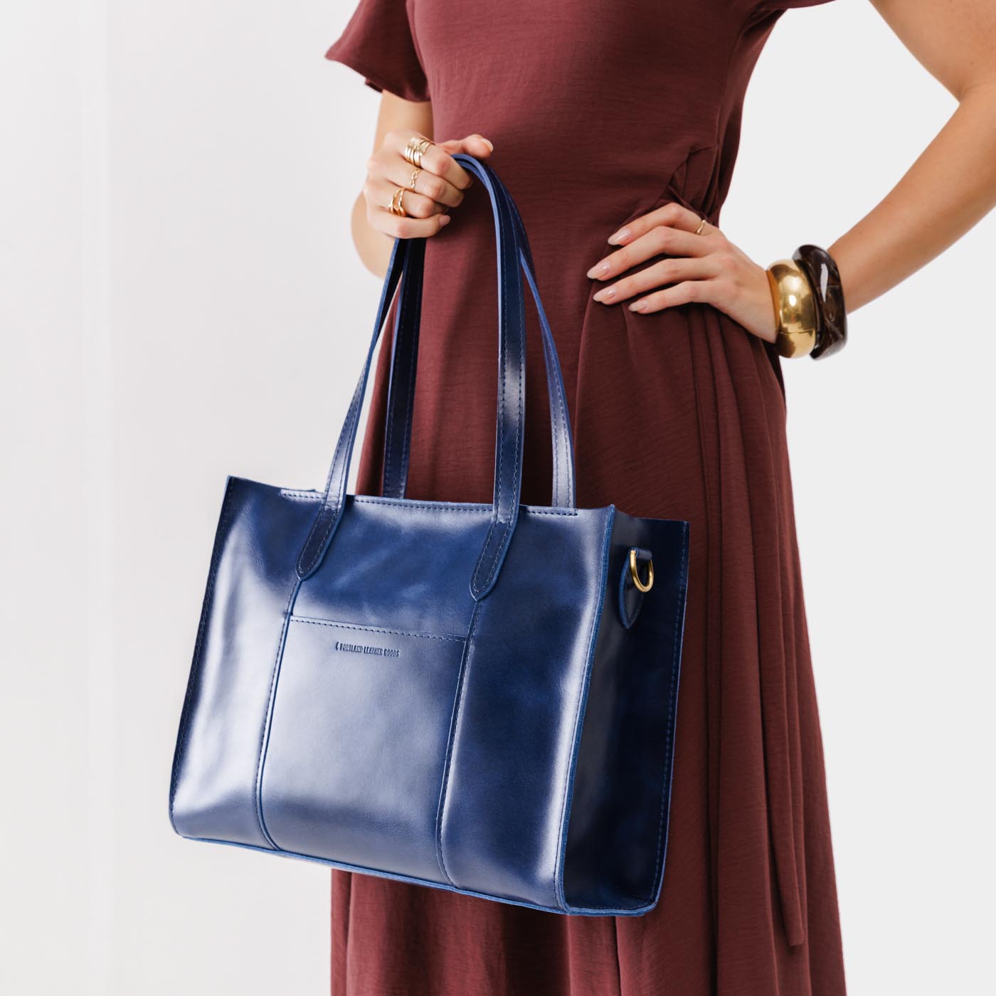 Cowboy Blue*East/West | Model holding structured wide tote bag with overlapping panels and crossbody strap