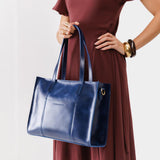 Cowboy Blue East/West | Model holding structured wide tote bag with overlapping panels and crossbody strap