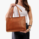 Honey East/West | Model holding structured wide tote bag with overlapping panels and crossbody strap