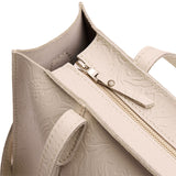 Jasmine | Close-up of zipper top on structured wide embossed leather tote bag with overlapping panels and crossbody strap