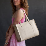 Jasmine | Model carrying structured wide embossed leather tote bag with overlapping panels and crossbody strap