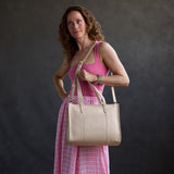 Jasmine | Model carrying structured wide embossed leather tote bag with overlapping panels and crossbody strap