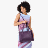 Empire East/West | Model holding structured wide tote bag with overlapping panels and crossbody strap