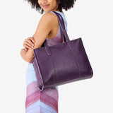 Empire East/West | Model holding structured wide tote bag with overlapping panels and crossbody strap