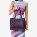 Empire East/West | Model holding structured wide tote bag with overlapping panels and crossbody strap