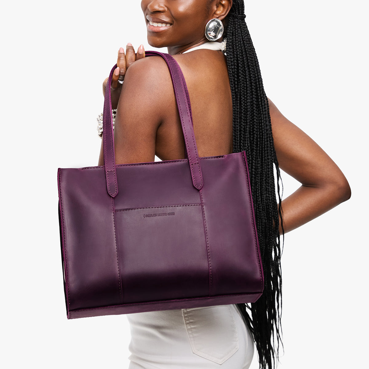 Larkspur*East/West | Model holding structured wide tote bag with overlapping panels and crossbody strap
