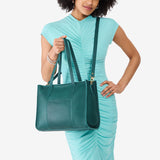 Sea Glass East/West | Model holding structured wide tote bag with overlapping panels and crossbody strap