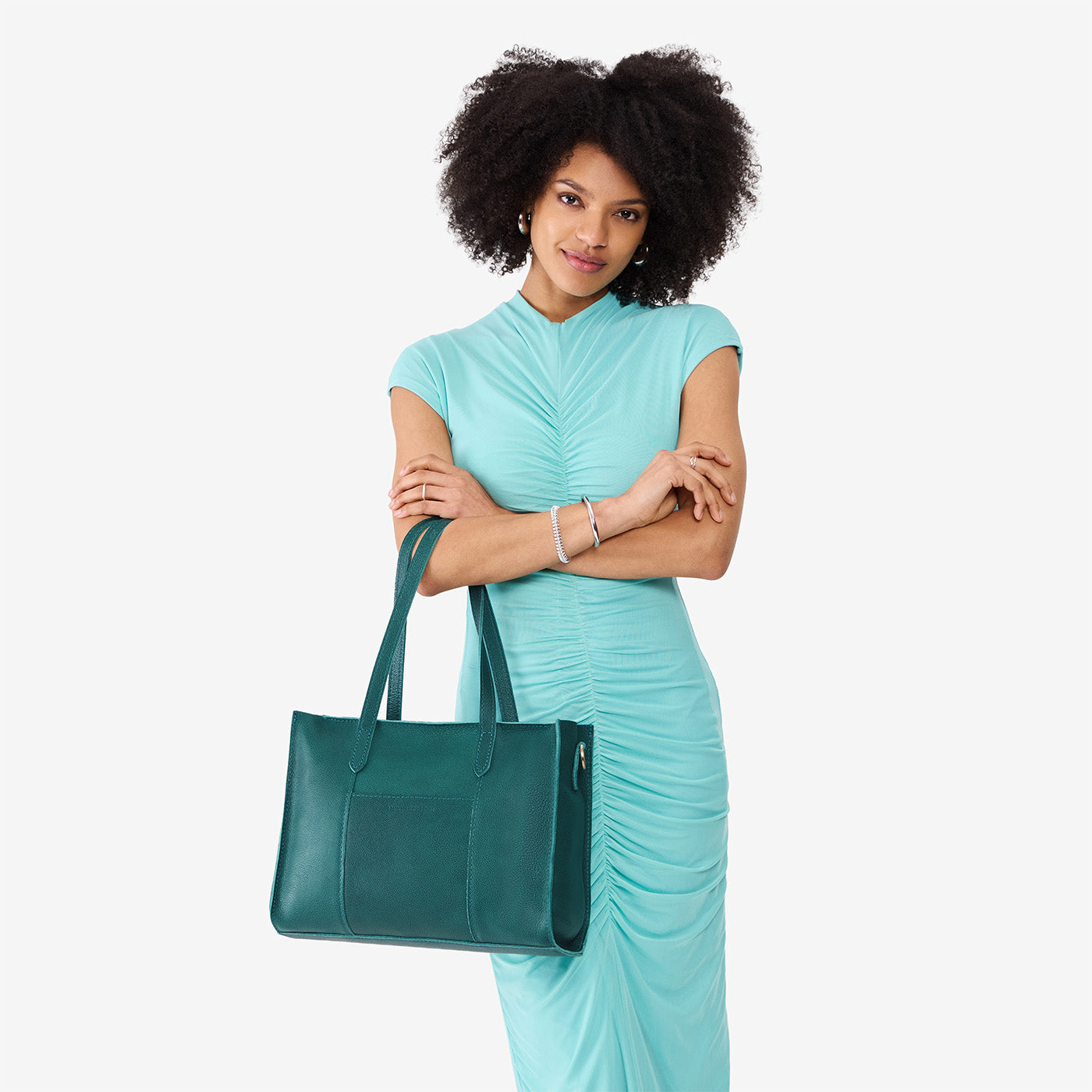 Sea Glass*East/West | Model holding structured wide tote bag with overlapping panels and crossbody strap