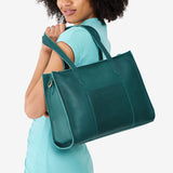 Sea Glass East/West | Model holding structured wide tote bag with overlapping panels and crossbody strap