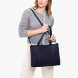 Velvet Blue East/West | Model holding structured wide tote bag with overlapping panels and crossbody strap