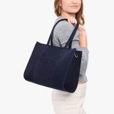 Velvet Blue East/West | Model holding structured wide tote bag with overlapping panels and crossbody strap