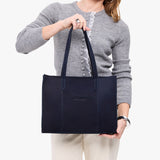 Velvet Blue East/West | Model holding structured wide tote bag with overlapping panels and crossbody strap