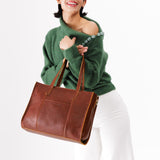 Nutmeg East/West | Model holding structured wide tote bag with overlapping panels and crossbody strap