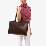 Chocolate Brown Oversized East/West | Model holding structured wide tote bag with overlapping panels and crossbody strap