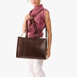 Chocolate Brown Oversized East/West | Model holding structured wide tote bag with overlapping panels and crossbody strap
