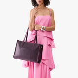 Larkspur Oversized East/West | Model holding structured wide tote bag with overlapping panels and crossbody strap