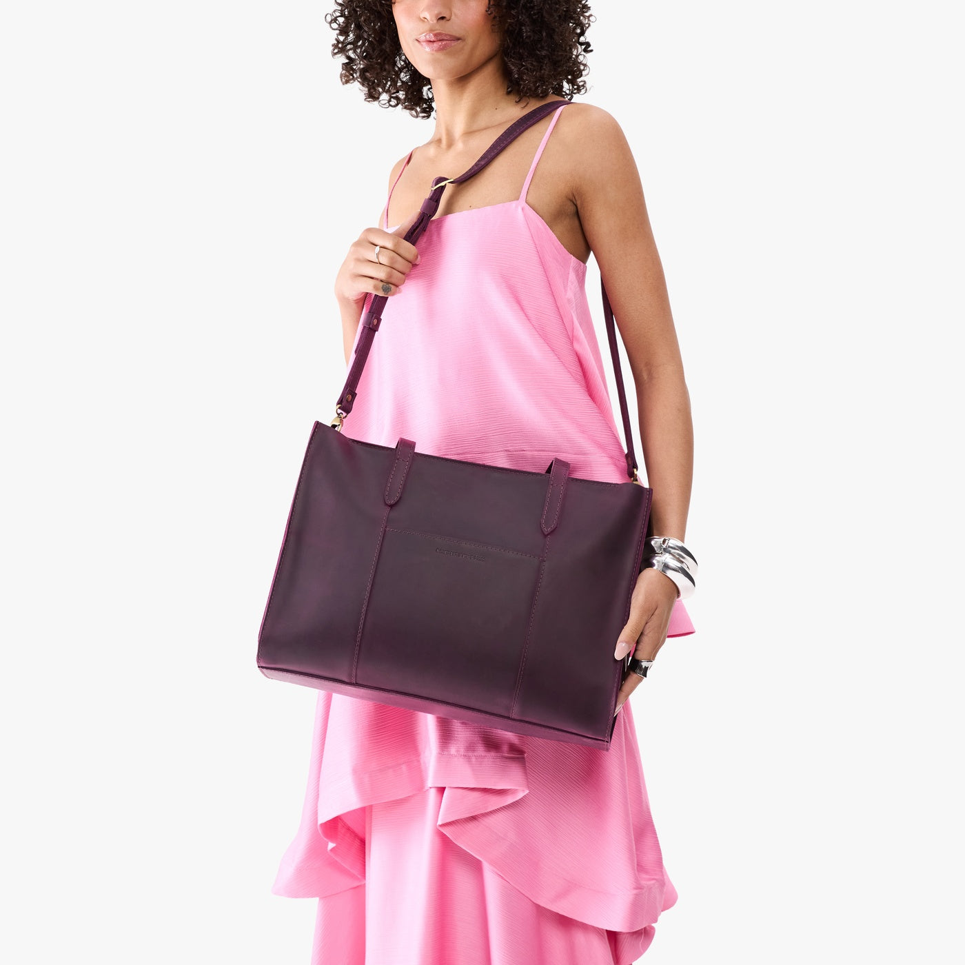 Larkspur*Oversized East/West | Model holding structured wide tote bag with overlapping panels and crossbody strap