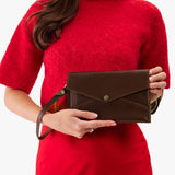 Chocolate Brown | Woman in a red dress holding a brown Envelope Crossbody against a white background