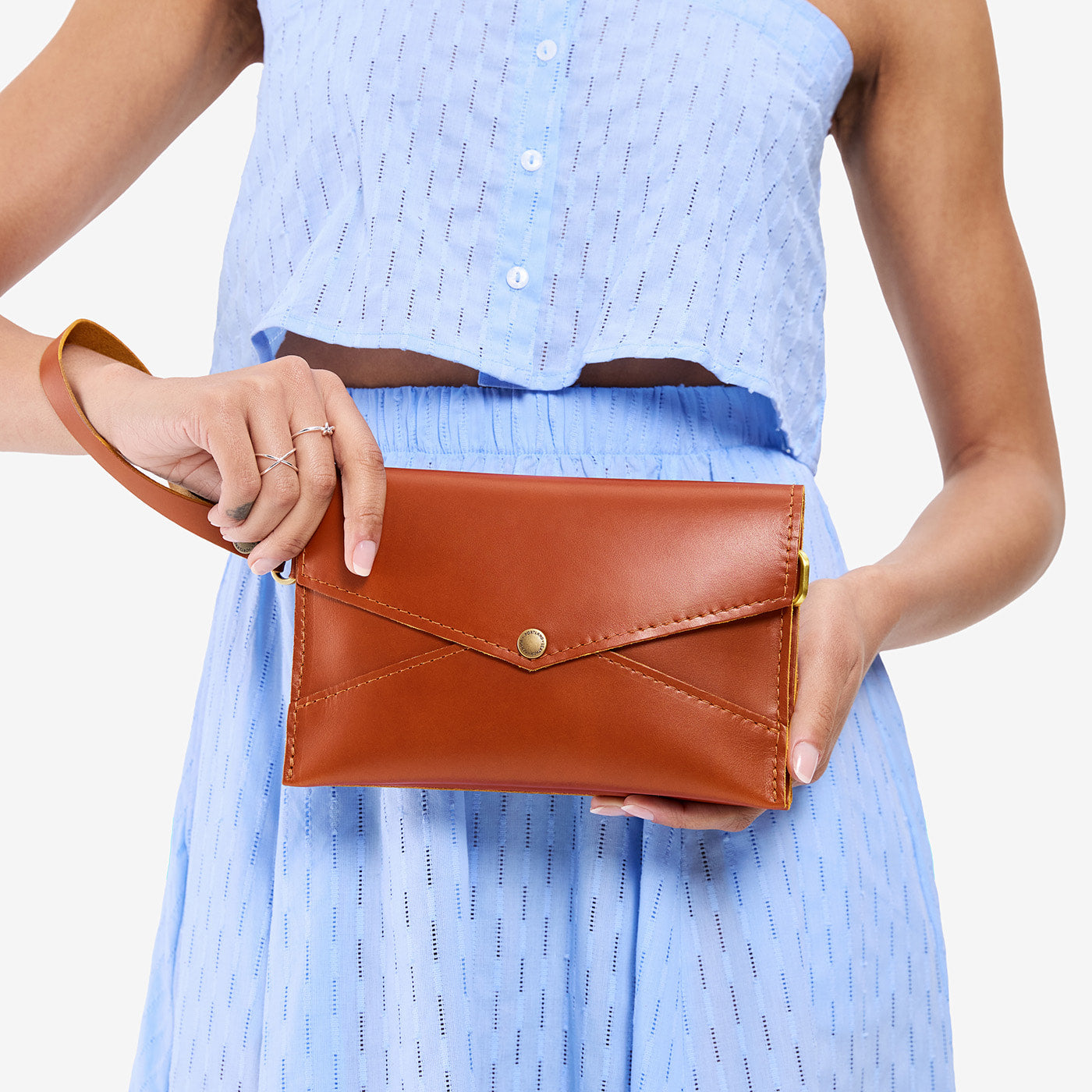 Madrone | Model holding envelope shaped clutch wallet with crossbody strap
